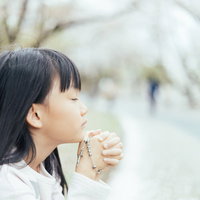 手を合わせて祈りを捧げるクリスチャンの子供の写真