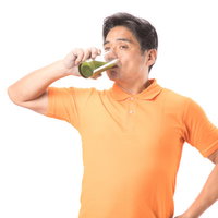 グラスの青汁をグビグビ飲む健康的な中年男性の写真