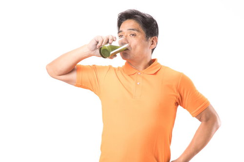 グラスの青汁をグビグビ飲む健康的な中年男性