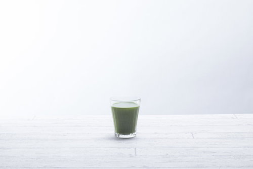 白いテーブルに置かれた青汁一杯の栄養ドリンク