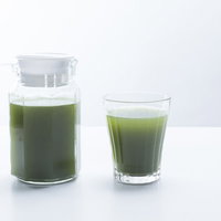 朝の青汁一杯とピッチャー、新鮮な野菜ジュースのヘルシードリンクの写真