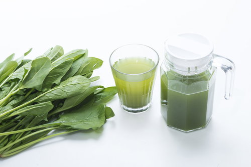 新鮮な葉物野菜とグラスに注がれた青汁、ポット