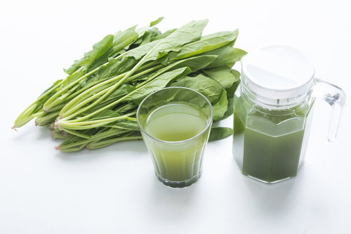 新鮮なほうれん草の束とガラスポットに入った青汁