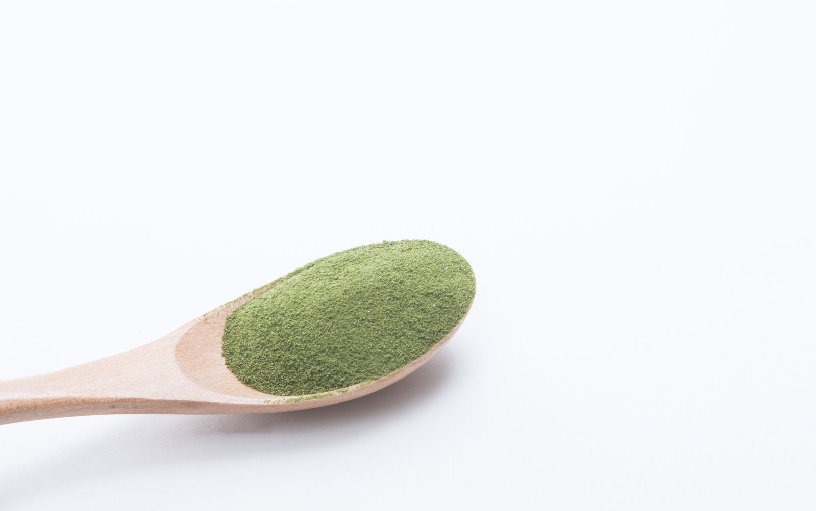 白い背景に木製スプーンに盛られた緑色の抹茶パウダー