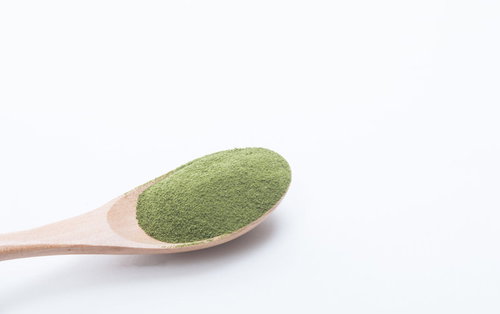 木製スプーン1杯の粉末青汁。抹茶風味の健康飲料