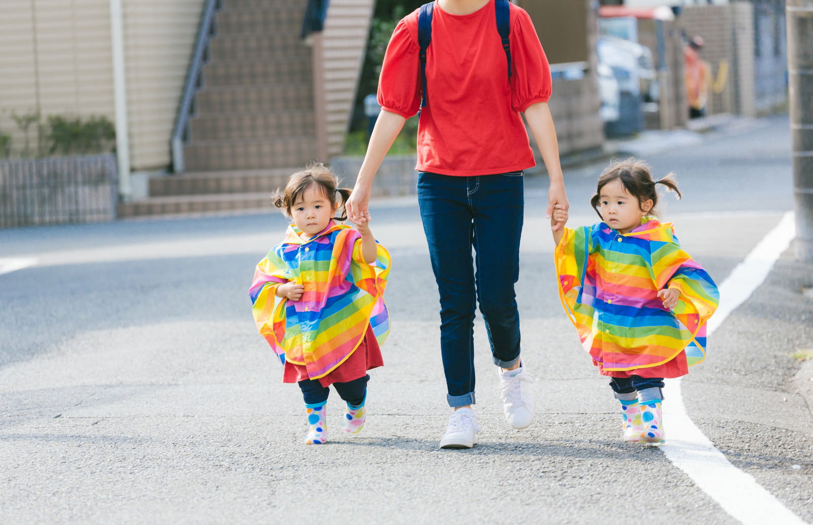 ママと手をつなぐ双子の女の子が歩道を歩いている様子［モデル：あおみどり］