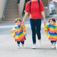ママと手をつなぎながら歩道を歩く双子の女児の写真