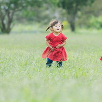 原っぱで並んで座る双子の女児、ツインテールで揃えたポーズの写真