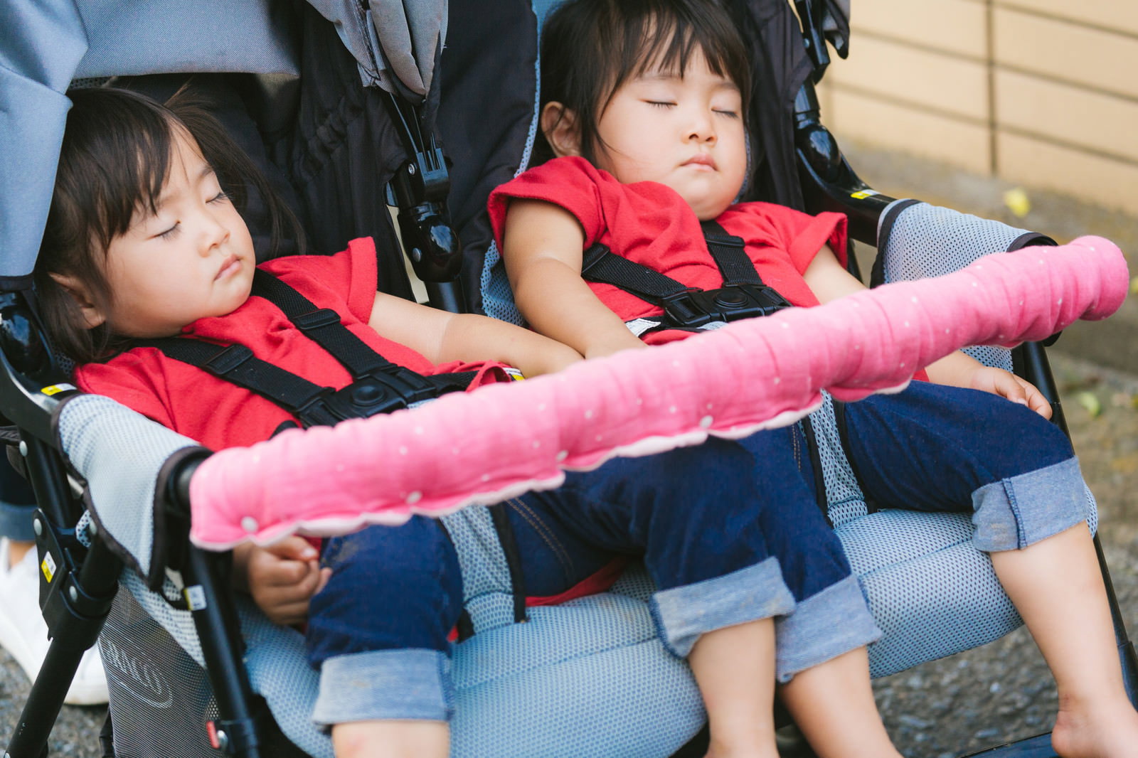 ベビーカーに座り赤いライフジャケットを着て眠る双子の女の子［モデル：あおみどり］