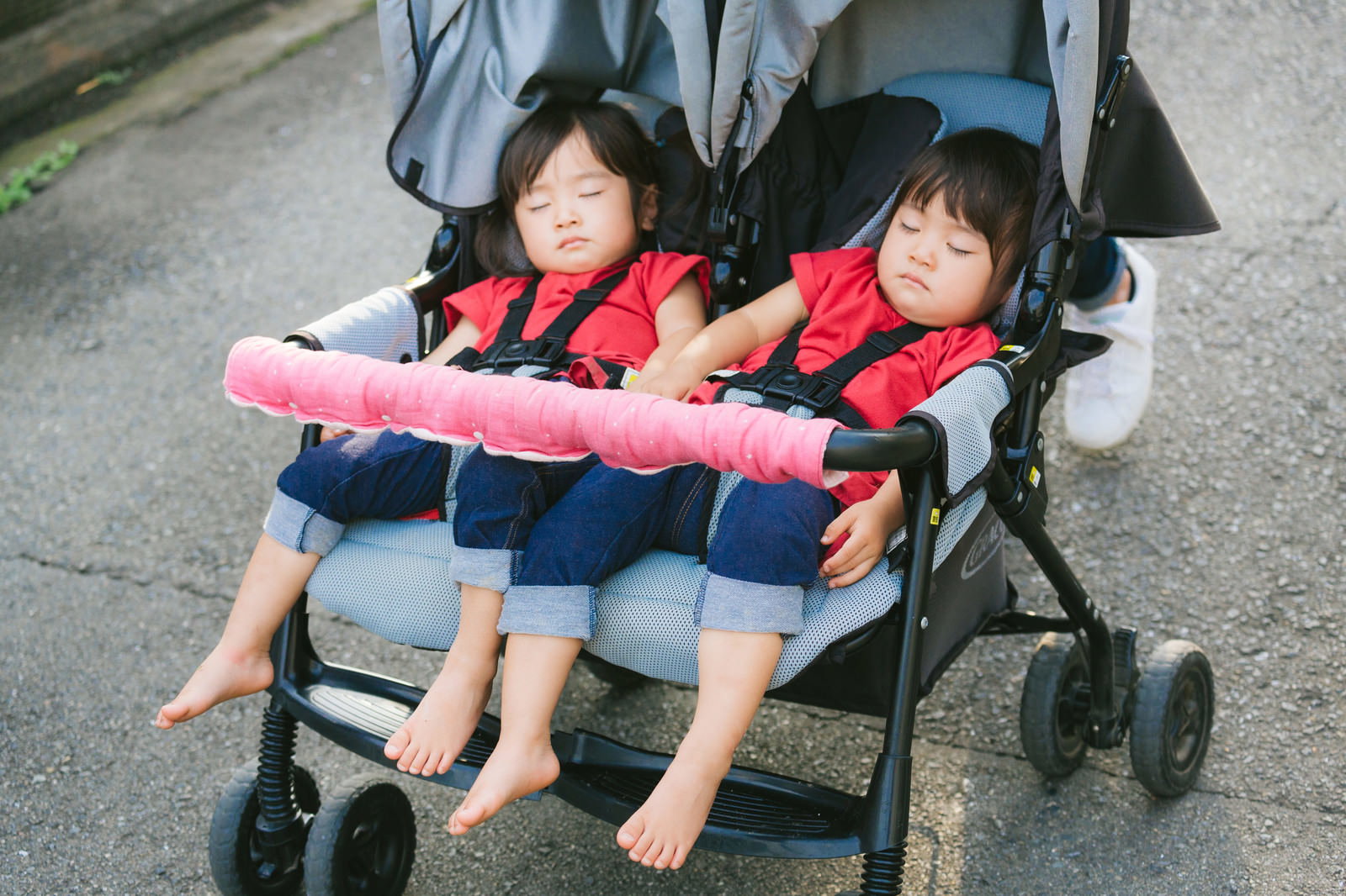 双子の幼児が二人乗りベビーカーで眠っている［モデル：あおみどり］