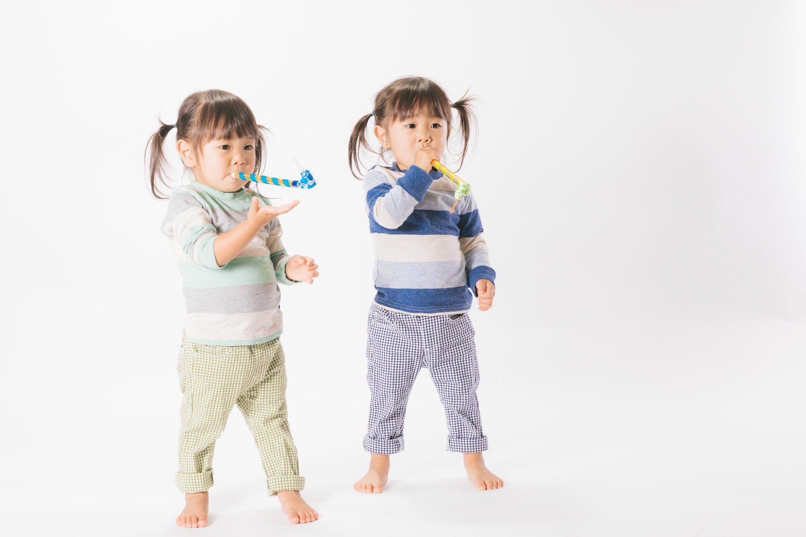 ピロピロプーで遊ぶ双子の女の子が並んで立っている様子［モデル：あおみどり］