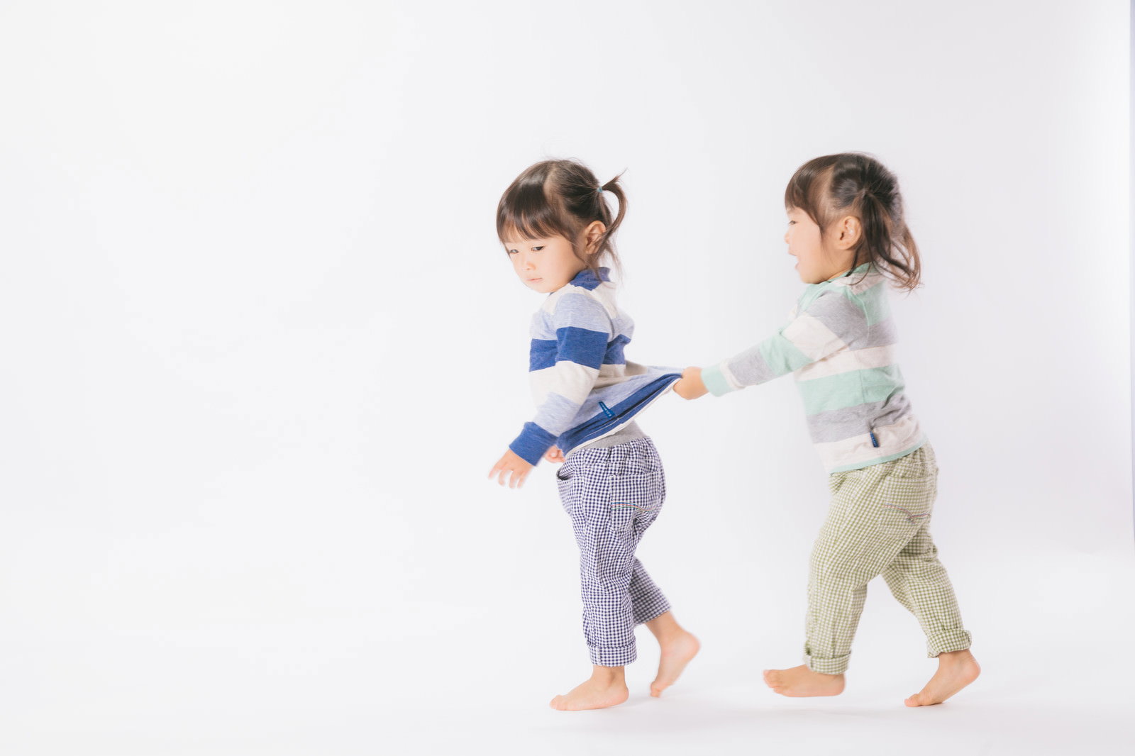 手をつないで仲良く歩く双子の女の子［モデル：あおみどり］