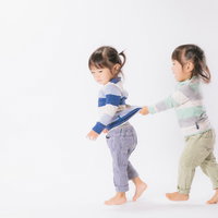 怒る姉と服をひっぱる妹の双子姉妹の兄弟姉妹関係の写真