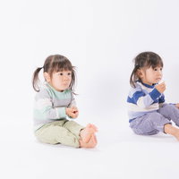 お菓子を与えるとおとなしくなる双子の子供たちの写真