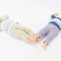 寝転ぶ姿も一緒の双子姉妹、白い背景でリラックスの写真