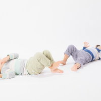 白い背景で寝そべる双子の女児、異なる色の服でリラックスの写真