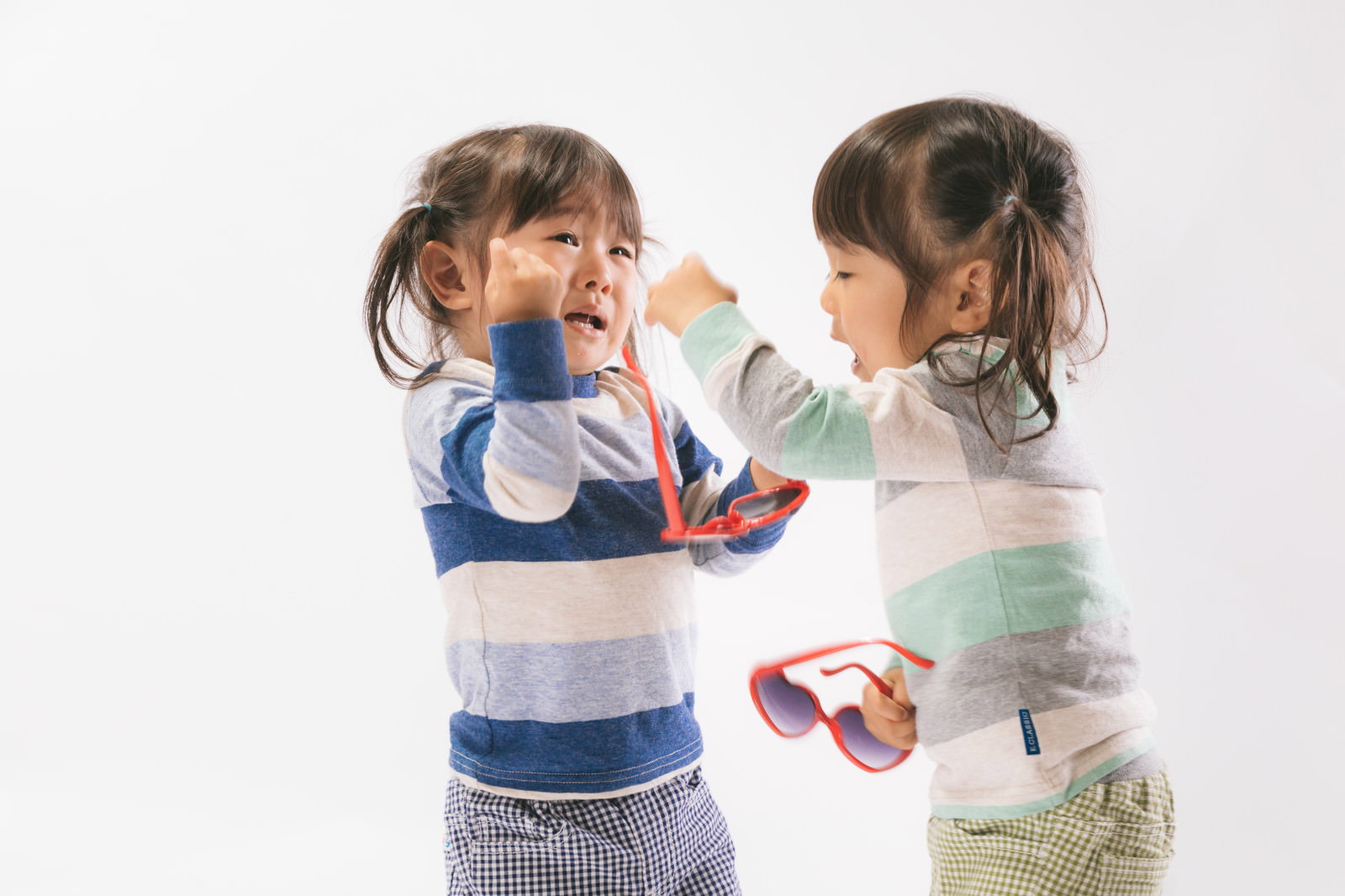 双子の女の子が取り合いをして喧嘩をしている様子［モデル：あおみどり］