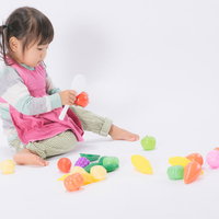 ピンクのエプロンを着ておままごとに夢中の女児の写真