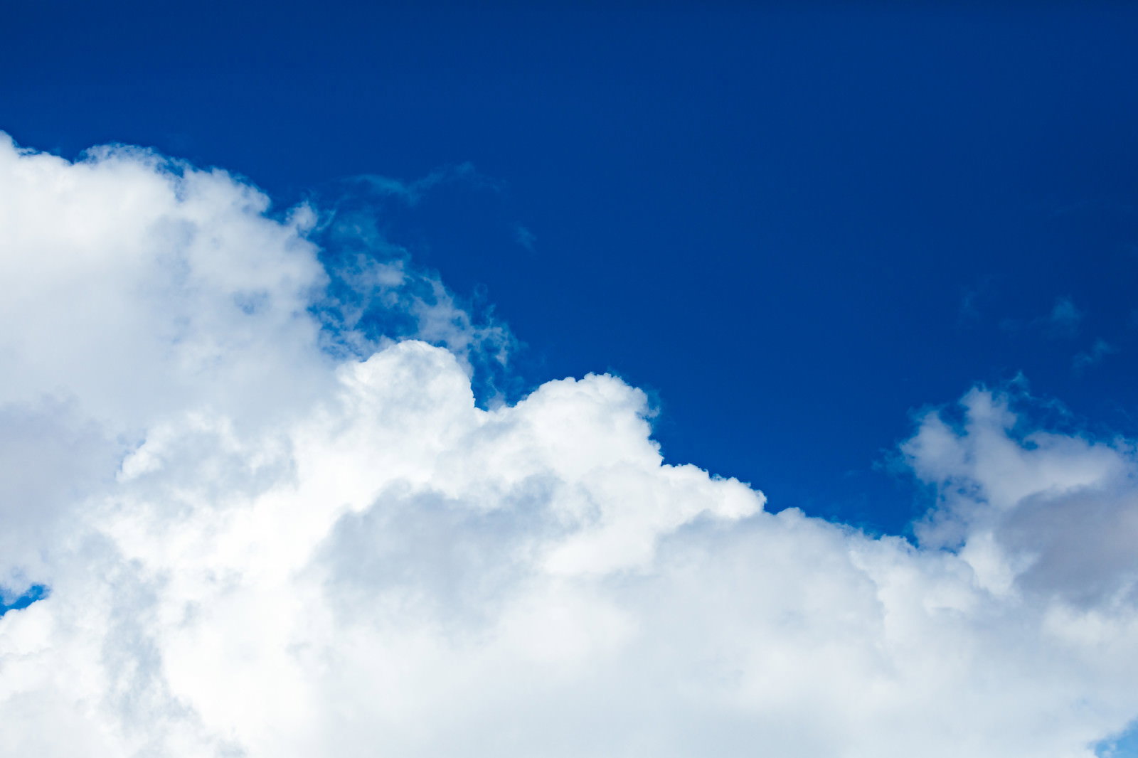 澄んだ青色の空に白い雲が浮かぶ夏の晴天の様子