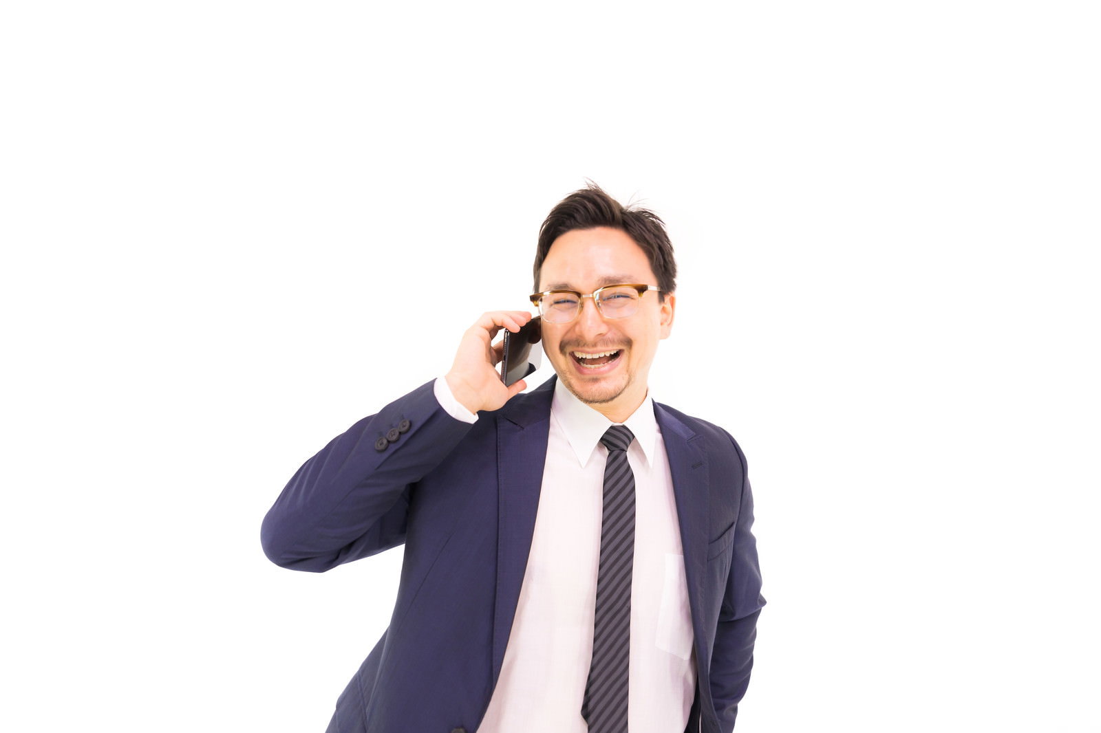 スマートフォンで通話しながら大笑いするスーツの男性［モデル：Max_Ezaki］