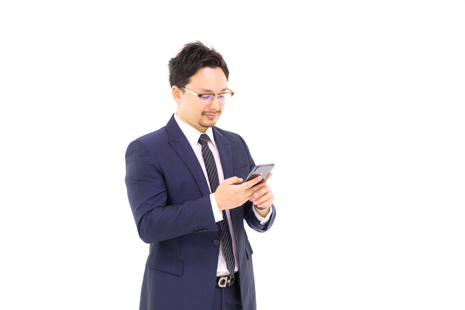紺色のスーツを着た男性がスマートフォンを操作している［モデル：Max_Ezaki］