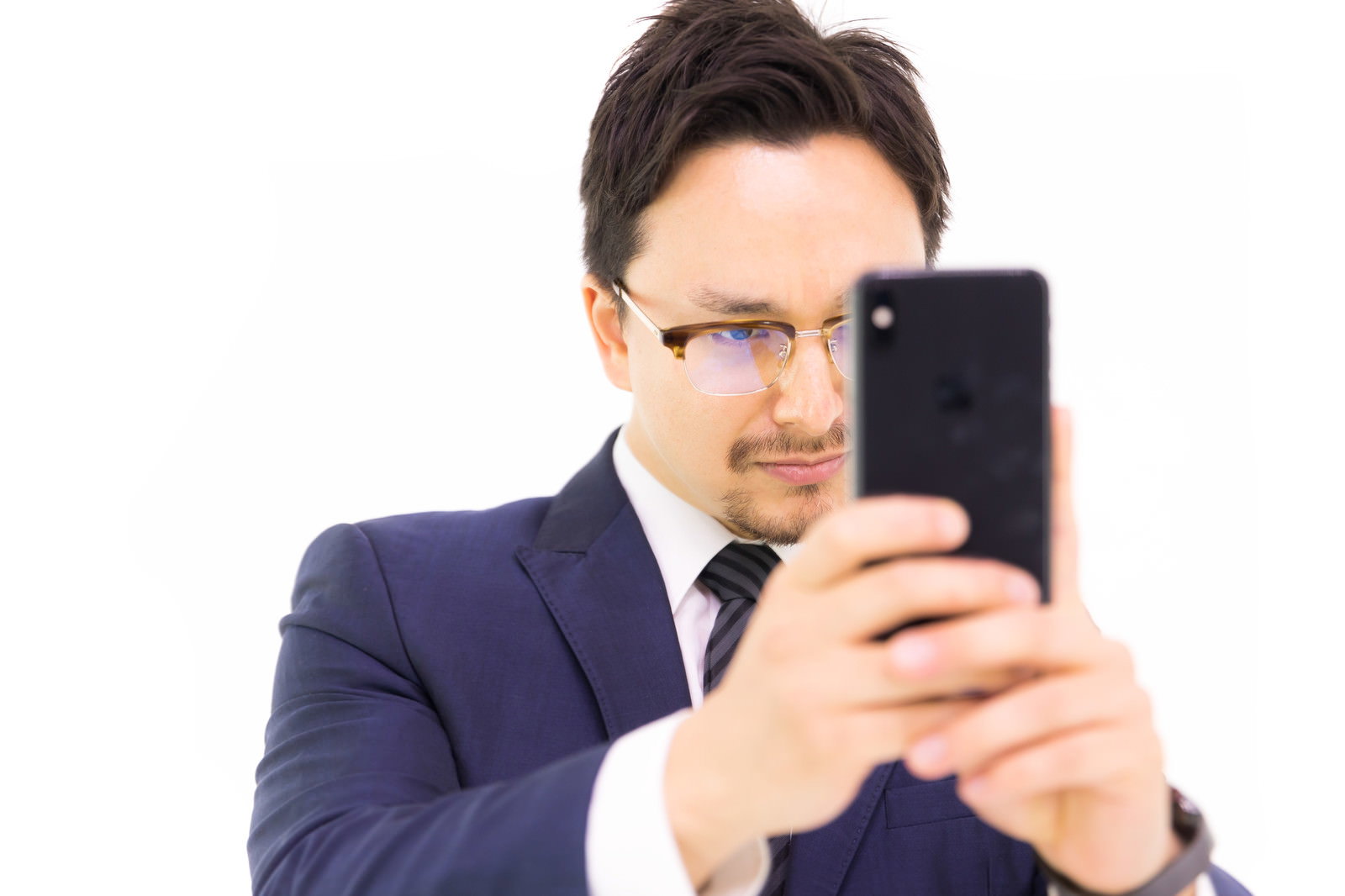 スーツ姿の男性がスマートフォンを縦向きに構えている［モデル：Max_Ezaki］