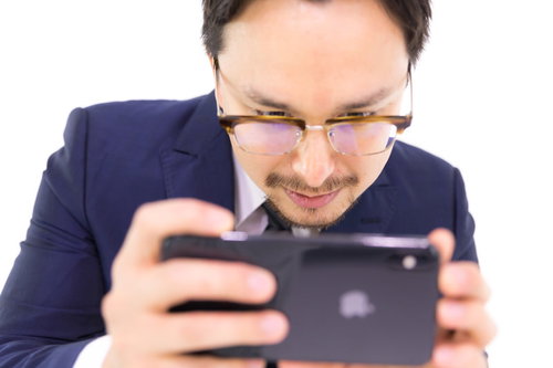 iPhone XS Maxで動画を見るビジネスマン