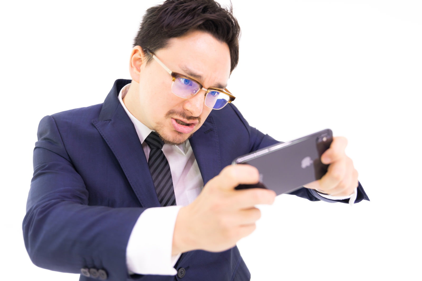 スマートフォンでゲームをプレイするスーツ姿の男性［モデル：Max_Ezaki］