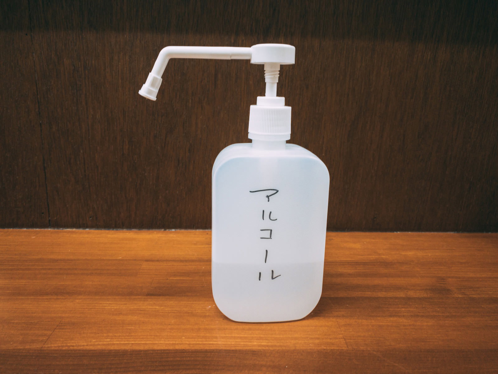 木製テーブルに置かれた白いポンプ式消毒液ボトル