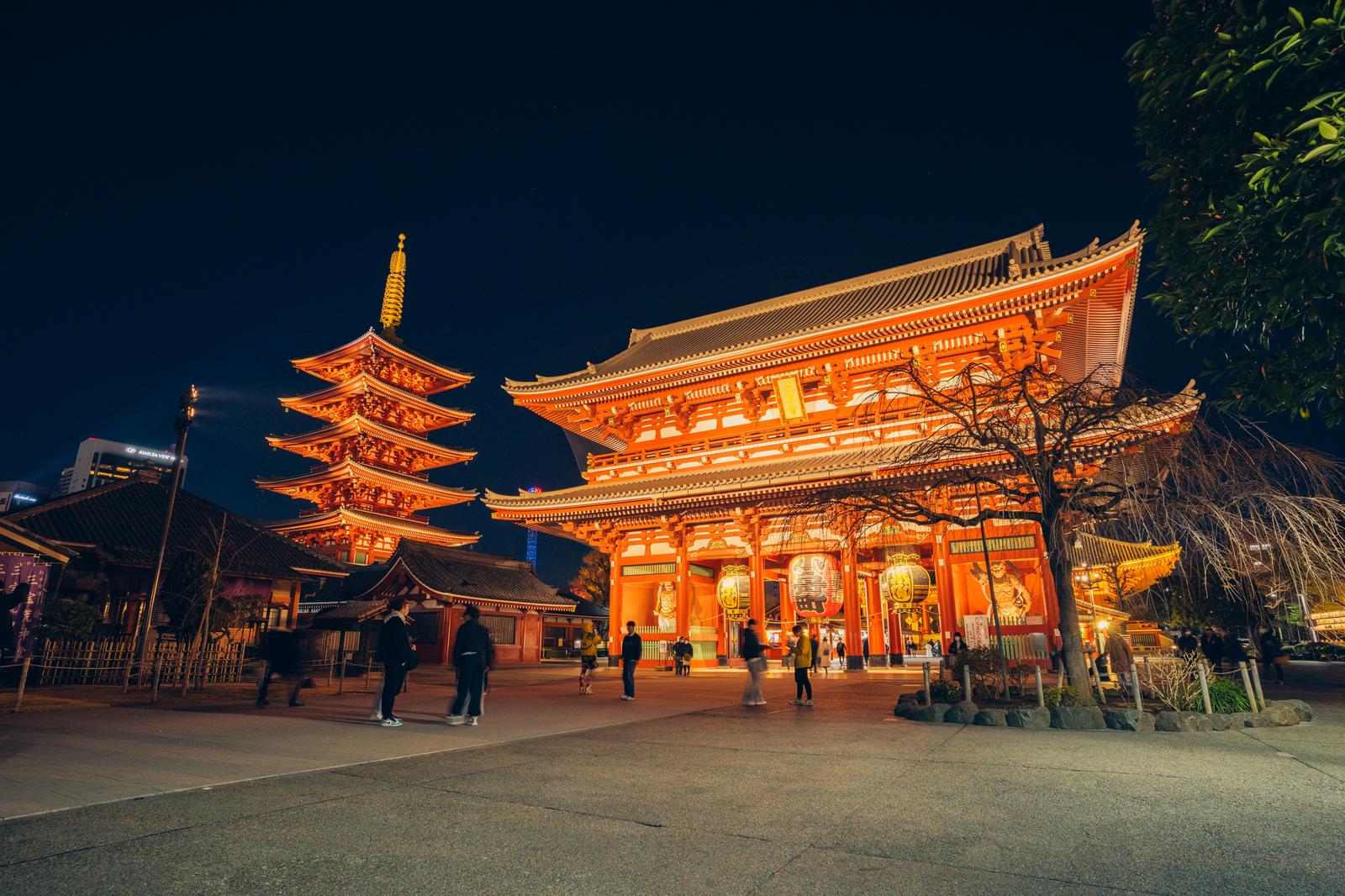 夜間ライトアップされた浅草寺の五重塔と本堂、参道を歩く観光客
