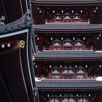 浅草の軒から見上げる五重塔、伝統的な朱色の木造建築と灰色の瓦屋根の写真