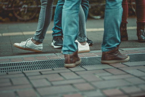 ジーンズを履いた複数人の足元と靴、歩道での集合シーン