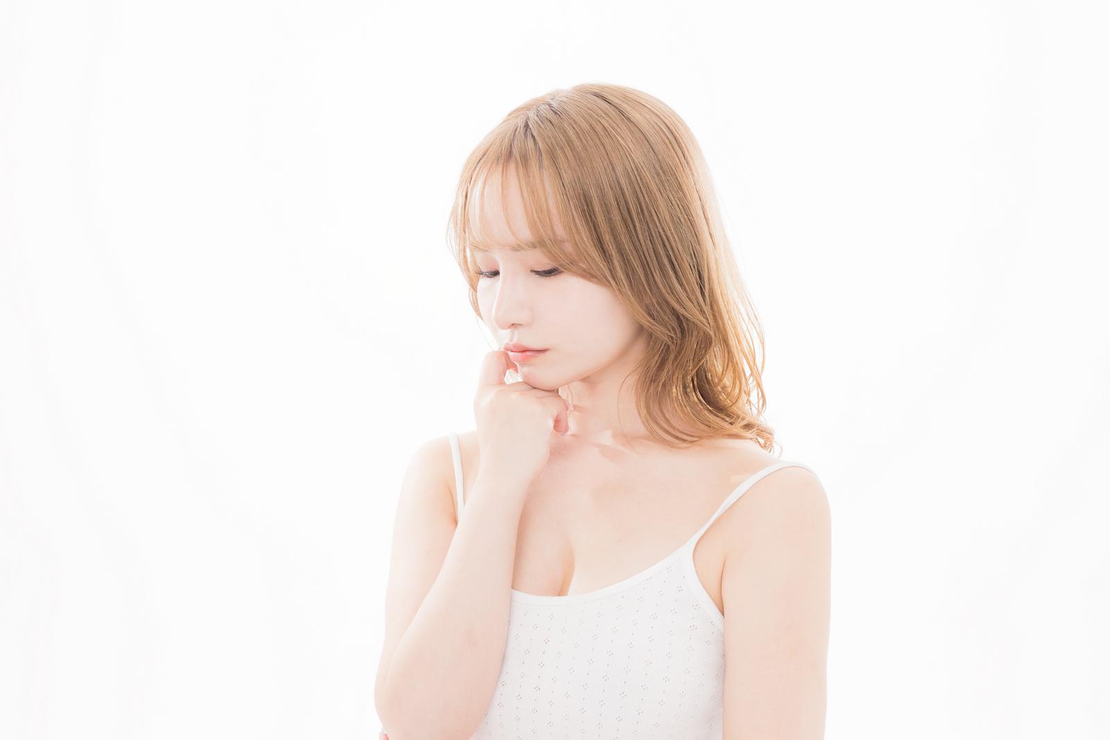 白いキャミソール姿で顔に手を当てて考える女性［モデル：yuria］