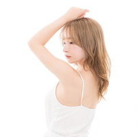 半身になって背中を見せてポーズを取る美容モデルのスキンケアの写真