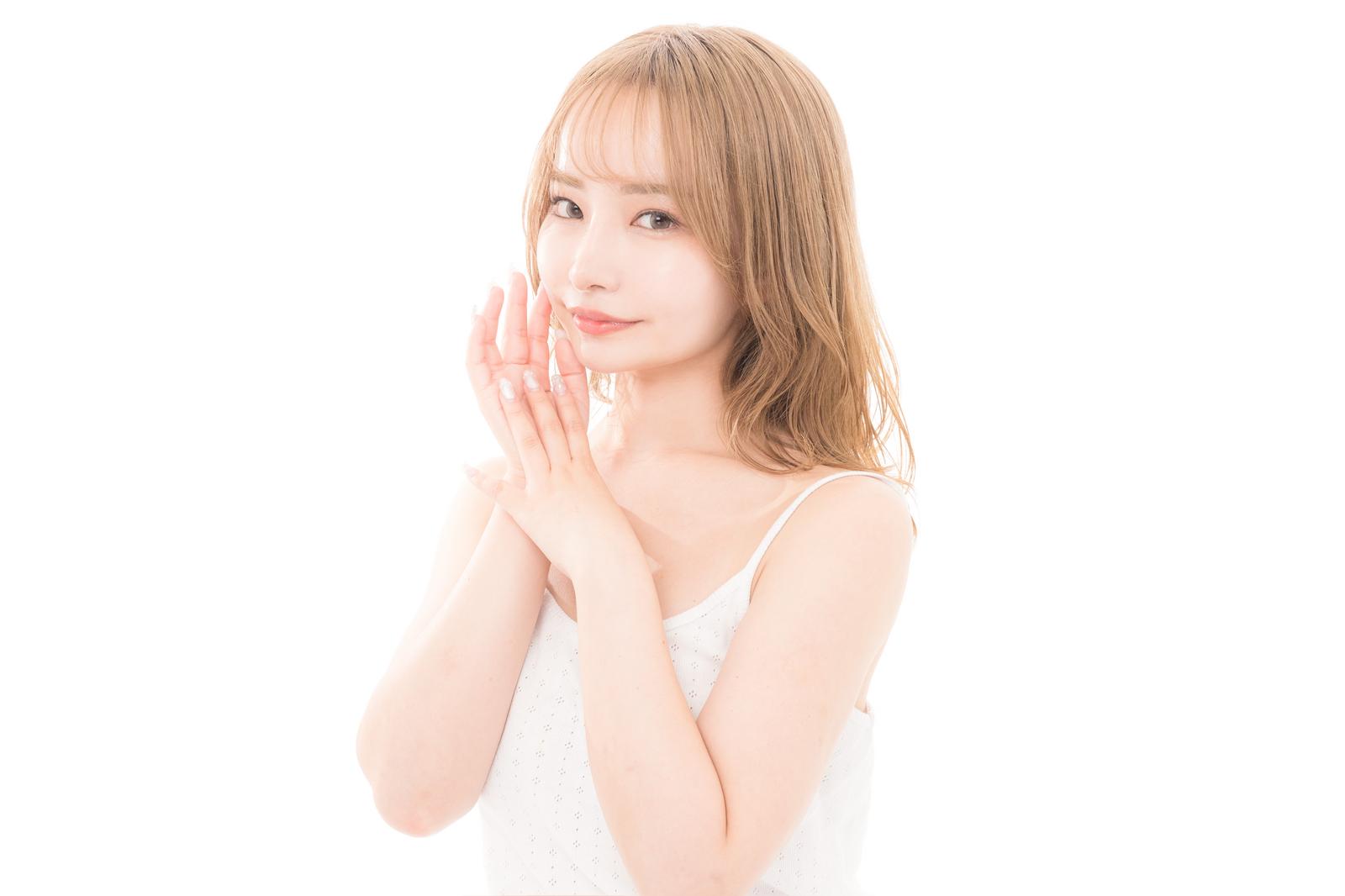 白いキャミソール姿で頬に手を添える透き通る肌の女性［モデル：yuria］