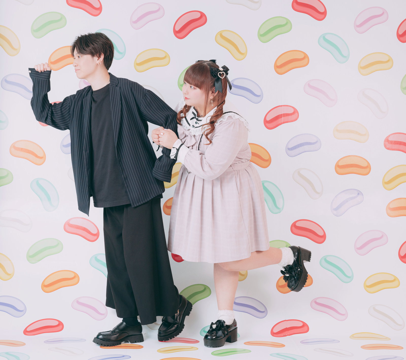 ピンクのワンピース姿でツインテールの女性が、スーツ姿の男性と腕を組んで立っている［モデル：あづき SHUN］