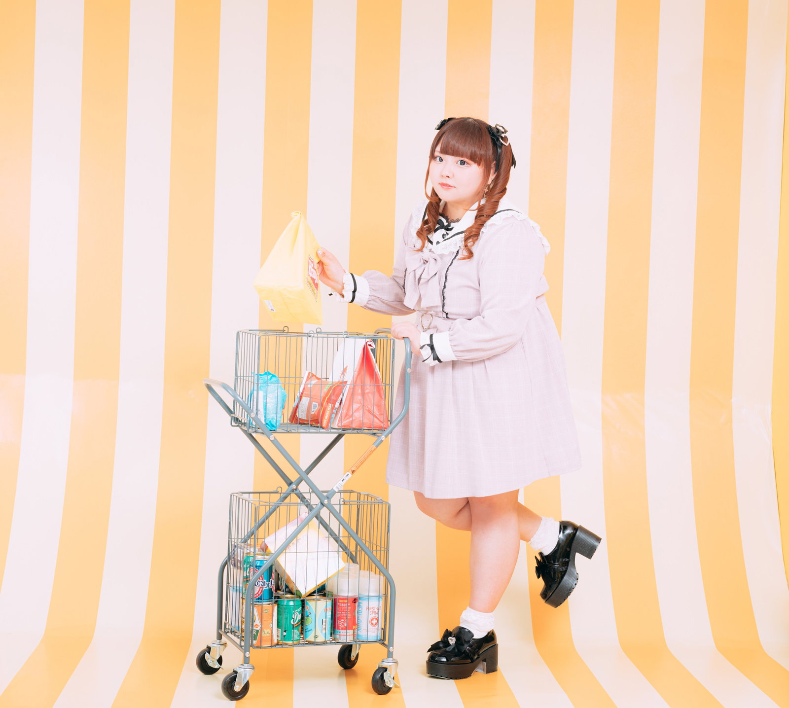 ツインテールの女性がピンク色のジャケット姿でショッピングカートから商品を取っている［モデル：あづき］
