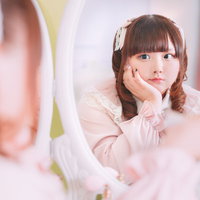 ミラーに映る自分を見つめるツインテール姿のぽっちゃり女性の写真