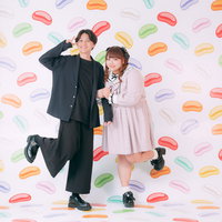 彼氏とツインテぽっちゃり女子がカラフルな背景で笑顔の写真