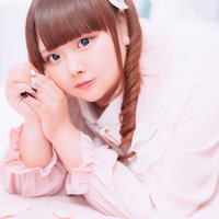 ピンクのフリルブラウスを着たこちらを見つめるぽちゃかわ女子の写真