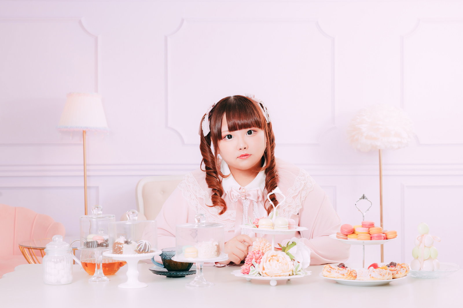 ツインテール姿の女性がティータイムを楽しみながらマカロンやスイーツを食べている様子［モデル：あづき］