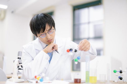 実験器具を使って分子構造モデルで研究する科学者