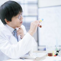 分子構造モデルを手に取りながら考え込む男性研究者の写真