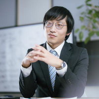 会議室で相手の主張に耳を傾ける眼鏡をかけた男性の写真