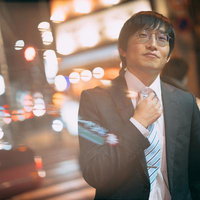 ネクタイを締めて夜のネオン街に消える眼鏡の会社員の写真