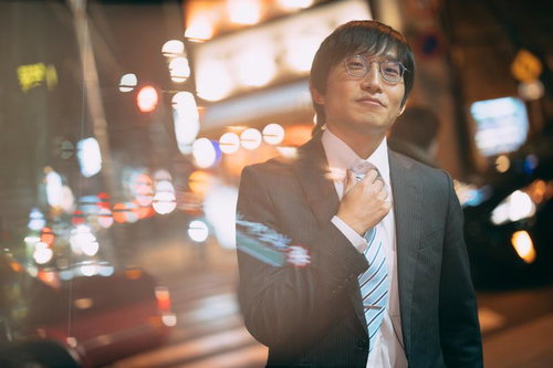 ネクタイを締めて夜のネオン街に消える眼鏡の会社員