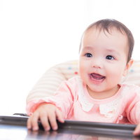 離乳食タイムを待ち望むピンクの服の赤ちゃんの写真