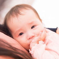 母親に抱かれて涙が溢れる赤ちゃんのギャン泣きの写真
