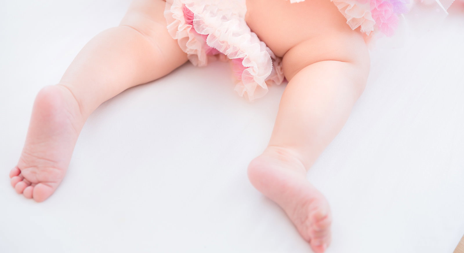 ピンク色のオムツを着用した乳幼児のムチムチした足［モデル：めぐな］