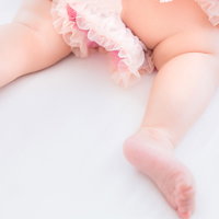 ピンク色のオムツを着用した乳幼児のムチムチな足の写真